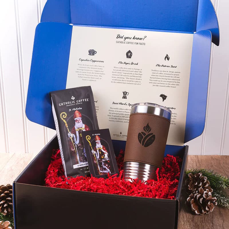 Catholic Coffee gift box with a brown tumbler and coffee bags on a wooden table.
