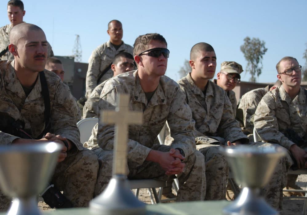 Group of military personnel sitting outdoors with crosses in front