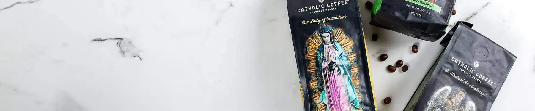 Catholic Coffee bags on a white marble table with coffee beans spread across.