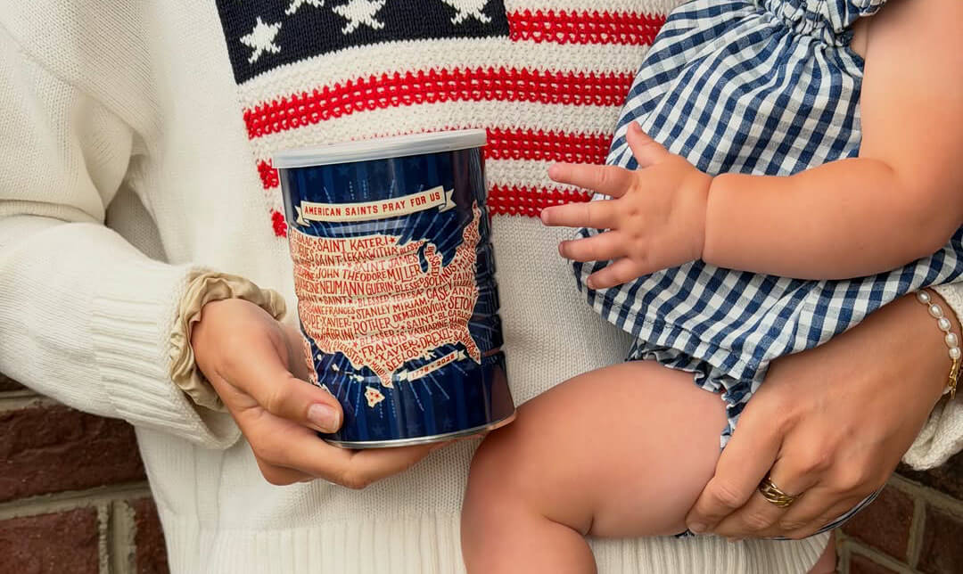 A person with an American flag sweater holding a tin coffee can in one hand and a baby in the other.